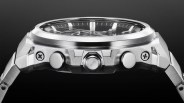 Close-up of a silver metal wristwatch side showing two push buttons, a crown, and screws on a black background.