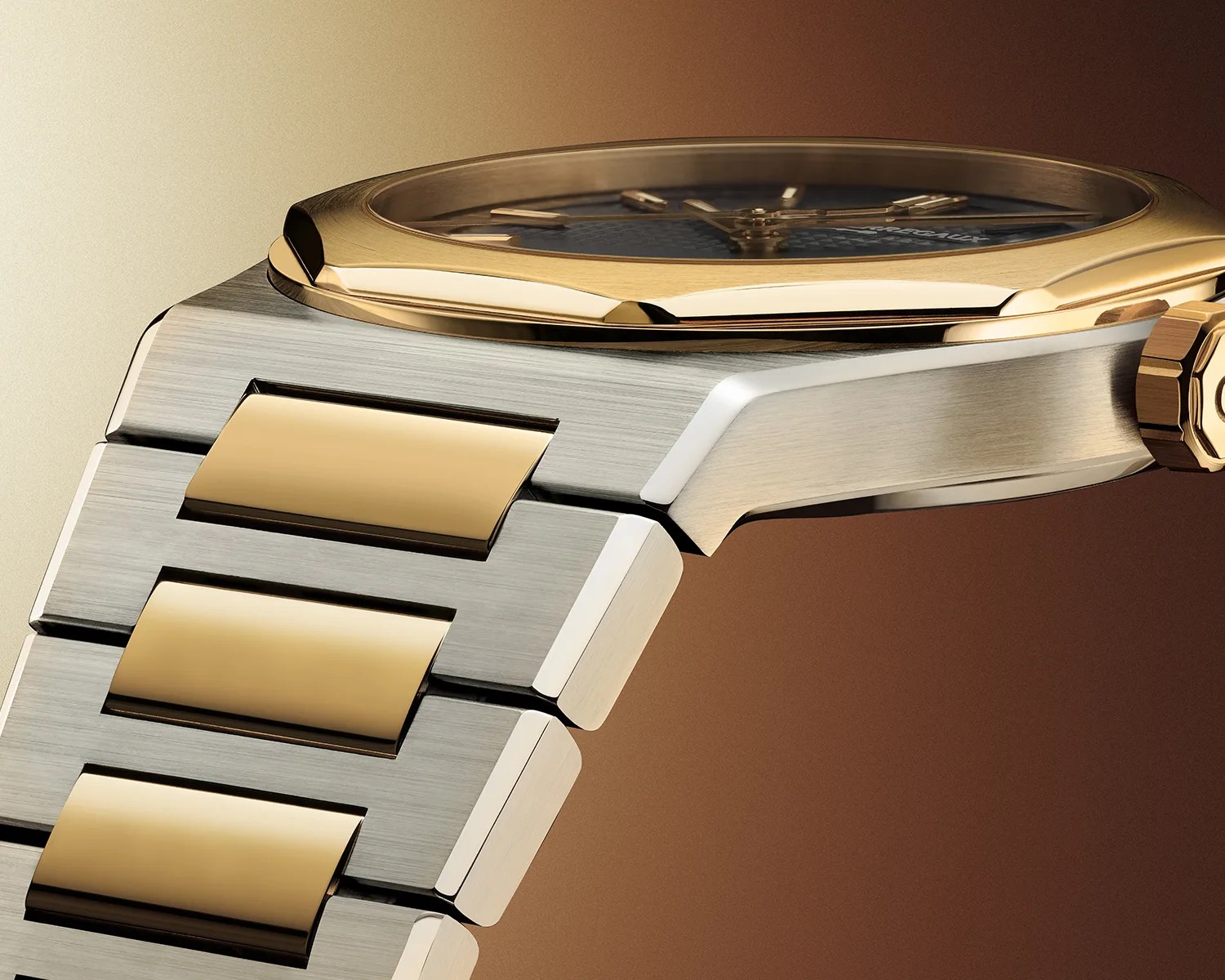 Close-up of a two-tone metal watch bracelet with brushed silver links and polished gold center links, attached to a gold bezel watch case.