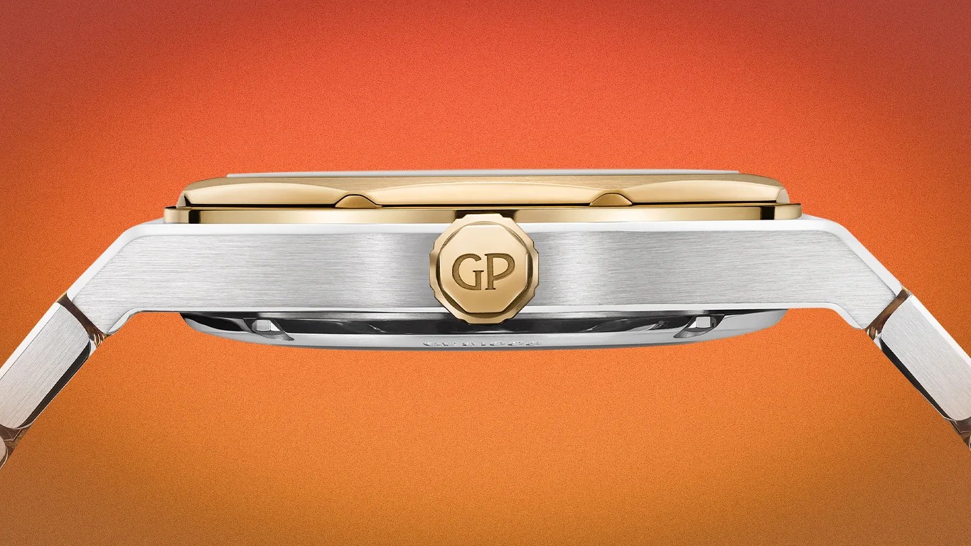 Side view of a silver and gold wristwatch with a gold crown engraved with "GP" on an orange background.