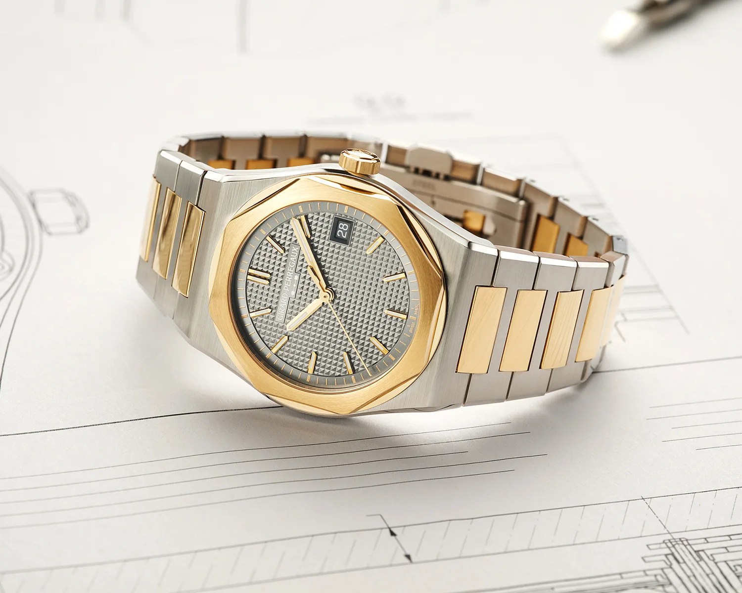 Two-tone stainless steel and gold wristwatch with a textured gray dial and date display on technical drawings.