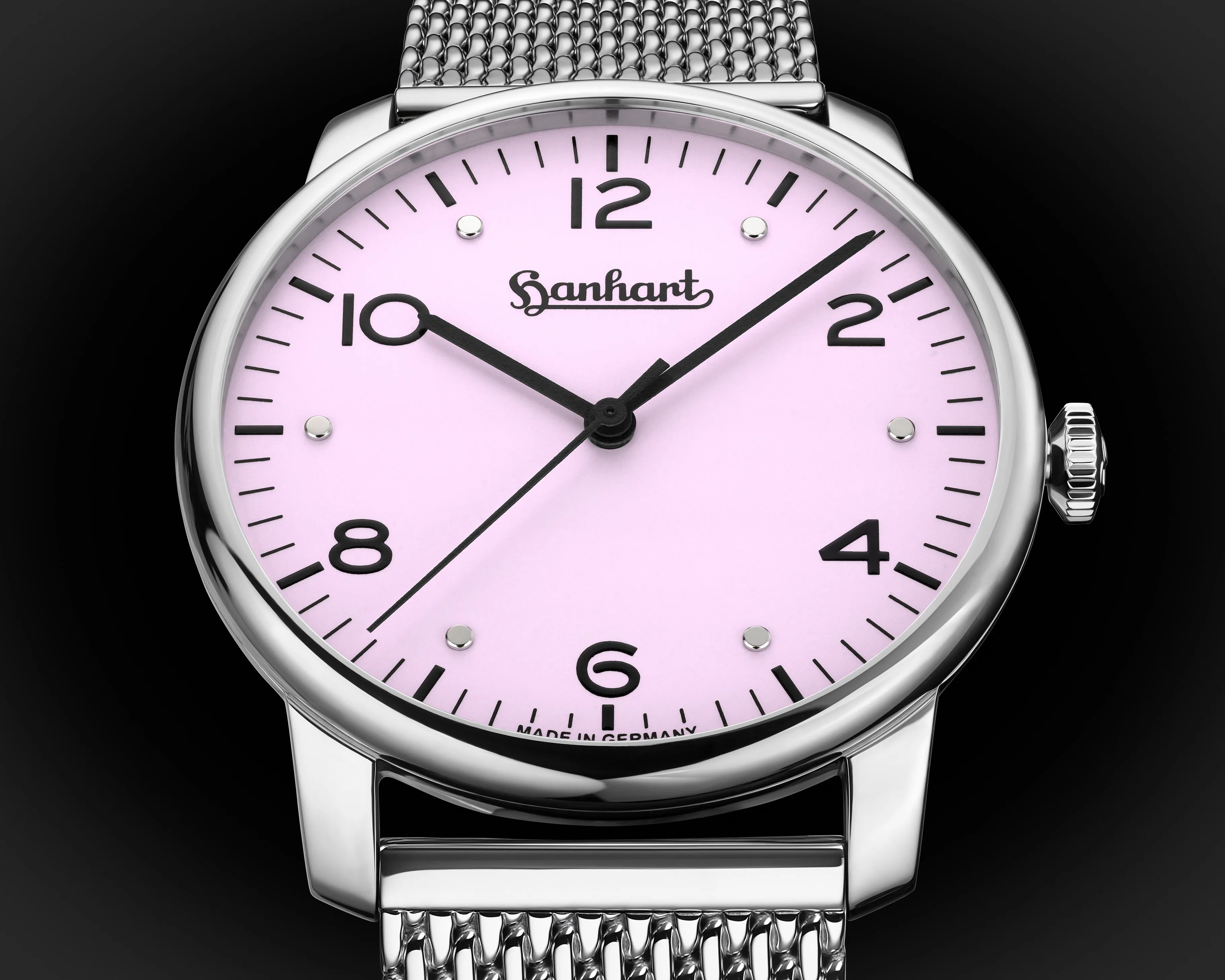 Silver wristwatch with a pink dial, black numerals, and a mesh metal strap on a black background.