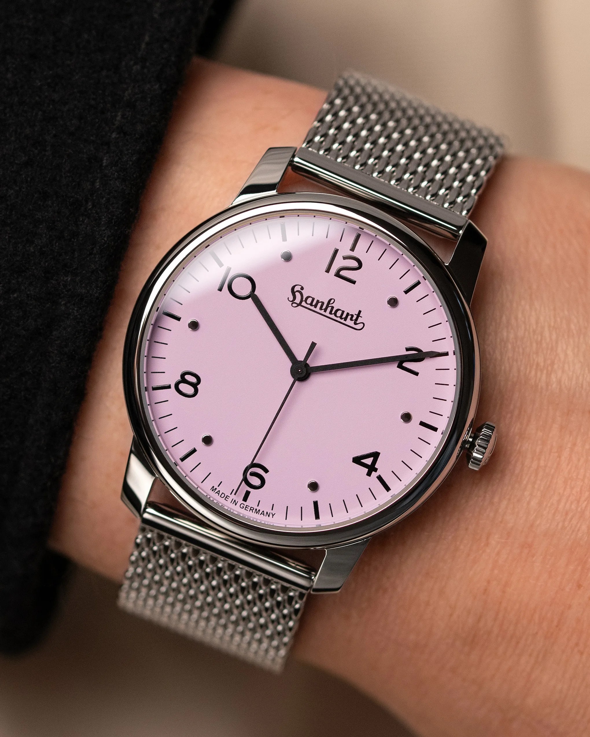 Silver mesh strap wristwatch with a pink dial and black numerals showing 10:10:32.