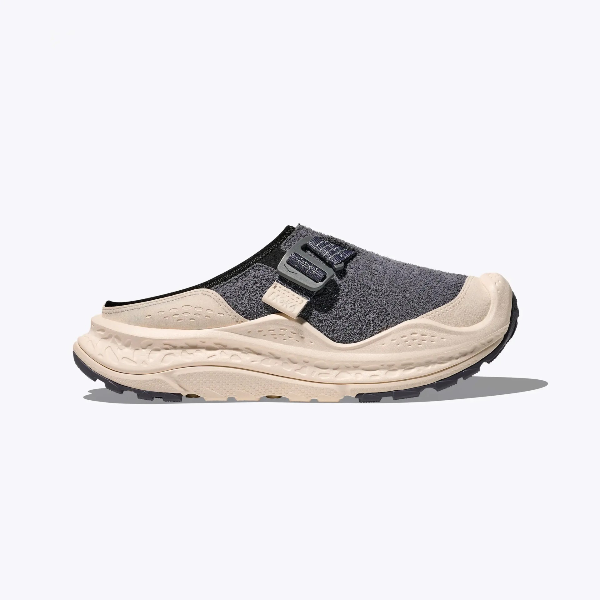 Beige and dark gray slip-on sneaker with textured upper and adjustable strap on a white background.
