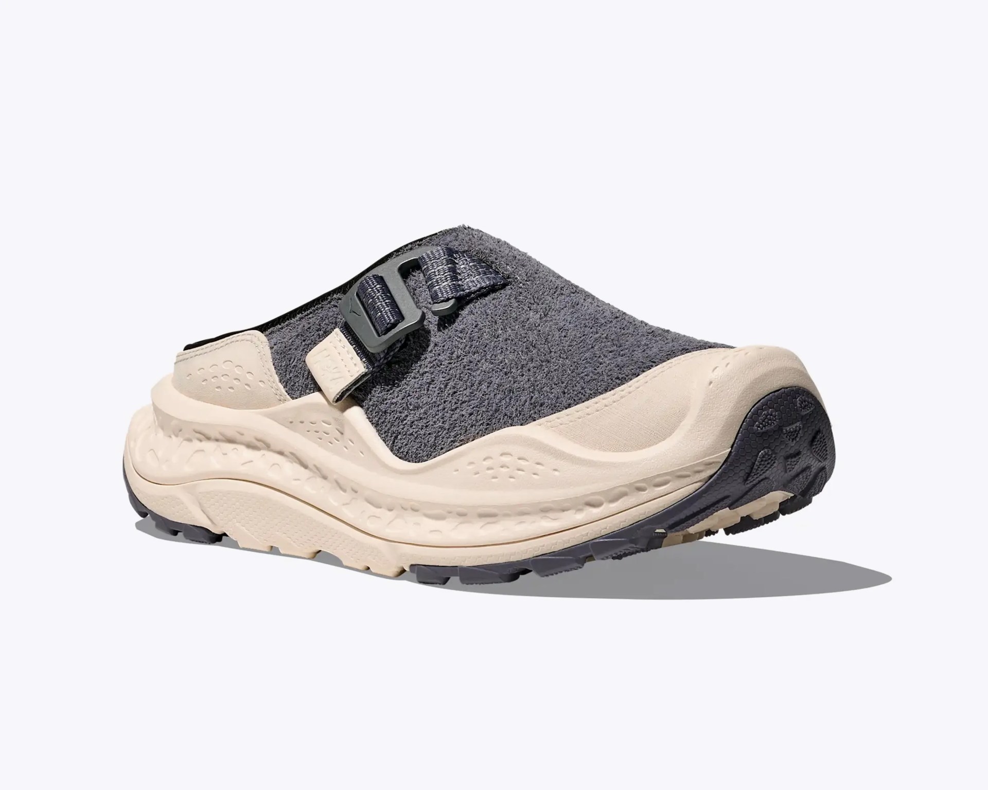 Beige and dark gray slip-on sandal with textured upper and adjustable strap on a white background.