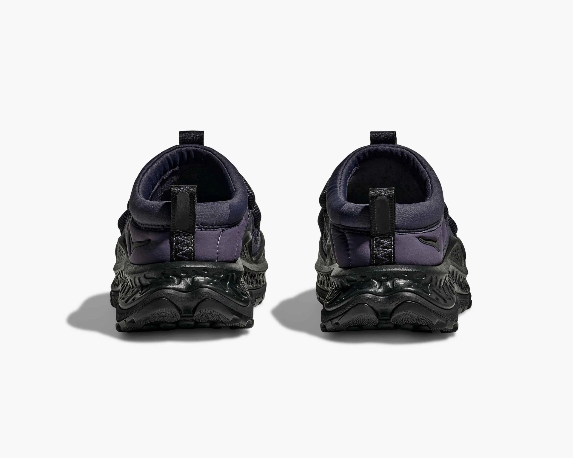 Pair of black and dark purple athletic shoes shown from the back with textured black soles and heel pull tabs.