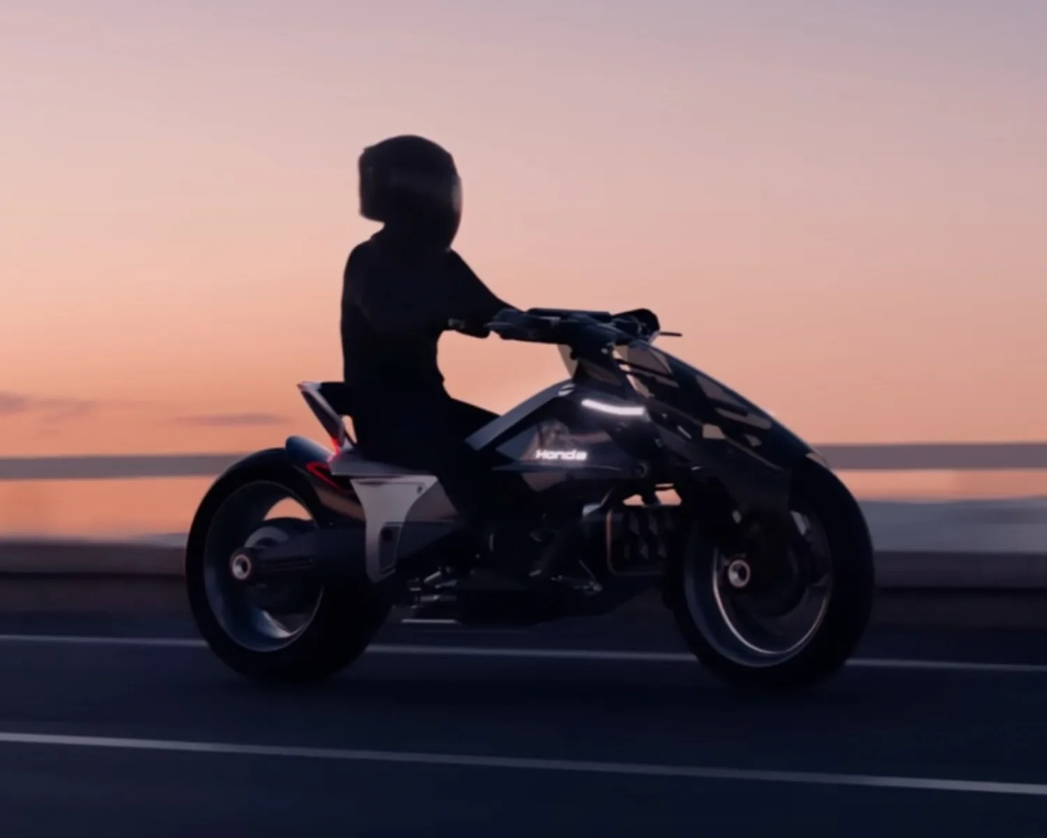 Person wearing a helmet riding a black Honda motorcycle at sunset on a road.