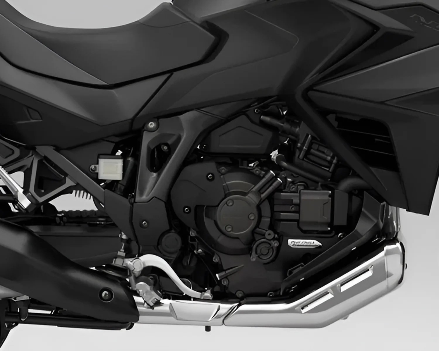 Close-up of a black motorcycle engine with a silver exhaust pipe and black frame components.