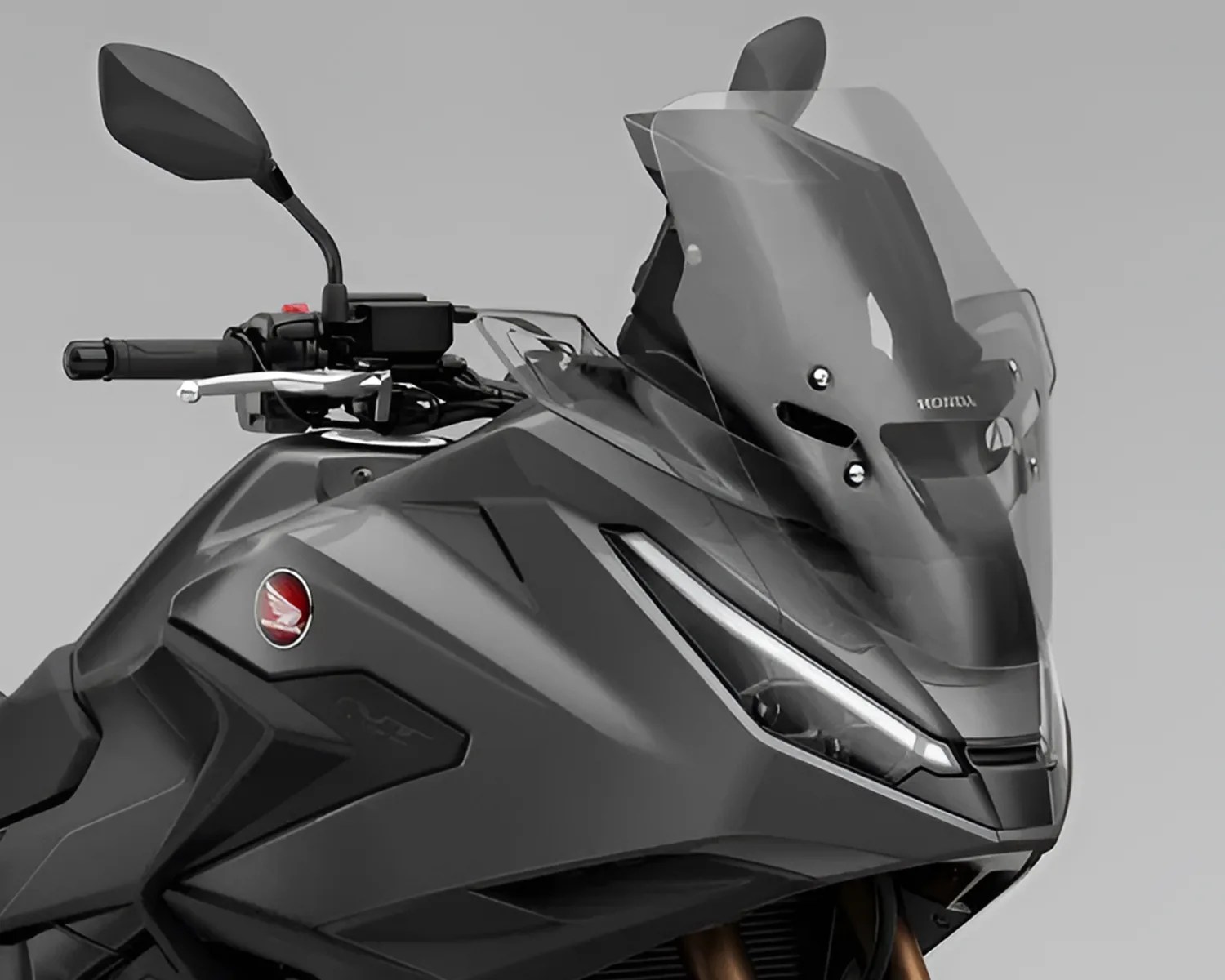 Close-up of a matte black Honda motorcycle front with angular headlight and tall tinted windshield.