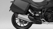 Rear section of a black Honda motorcycle showing the rear wheel, exhaust pipe, and side pannier.