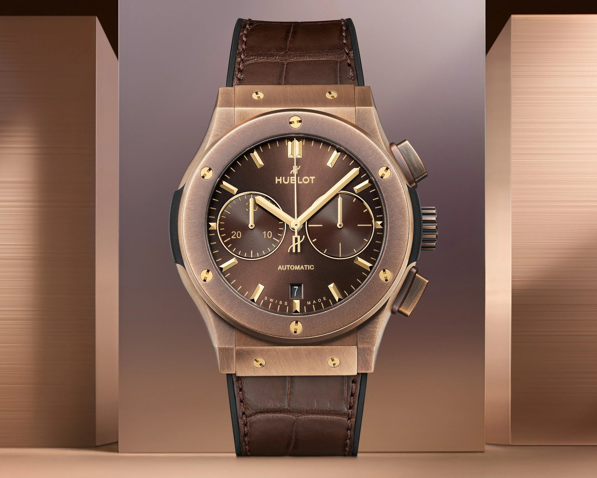 Brown Hublot automatic wristwatch with gold-tone case, chronograph subdials, and brown leather strap.