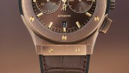 Close-up of a bronze automatic wristwatch with gold accents and a brown leather strap.