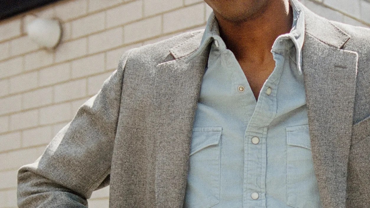 Light blue button-up shirt with chest pockets under a gray wool blazer.