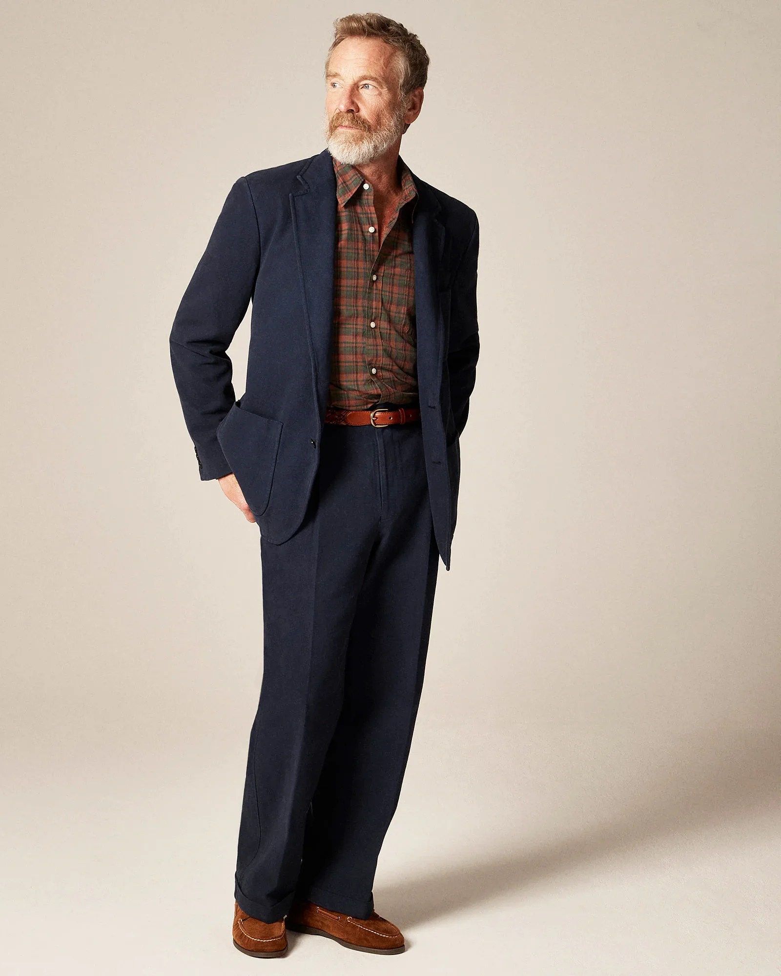 Man wearing a navy blazer and trousers with a brown plaid shirt, brown belt, and brown suede loafers.