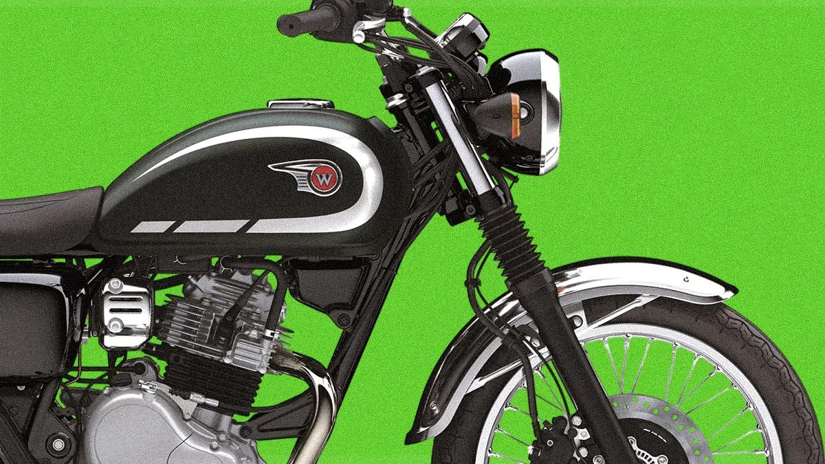 Black and silver classic motorcycle fuel tank and front wheel against a green background.