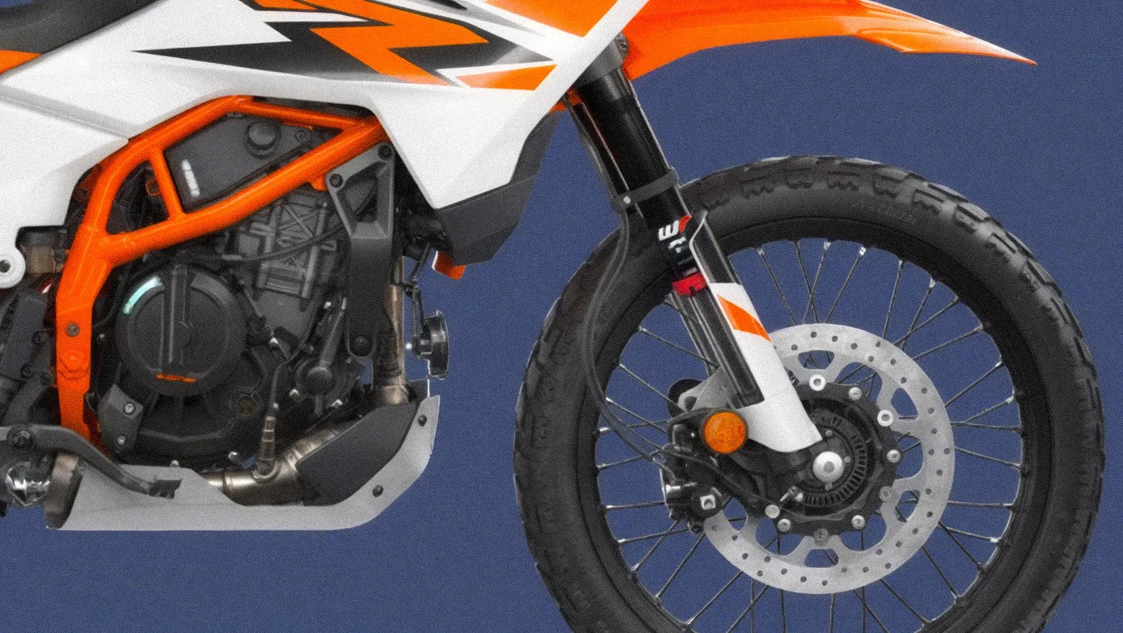 Close-up of a motorcycle's front wheel, suspension fork with orange and white graphics, and part of the engine frame in orange.