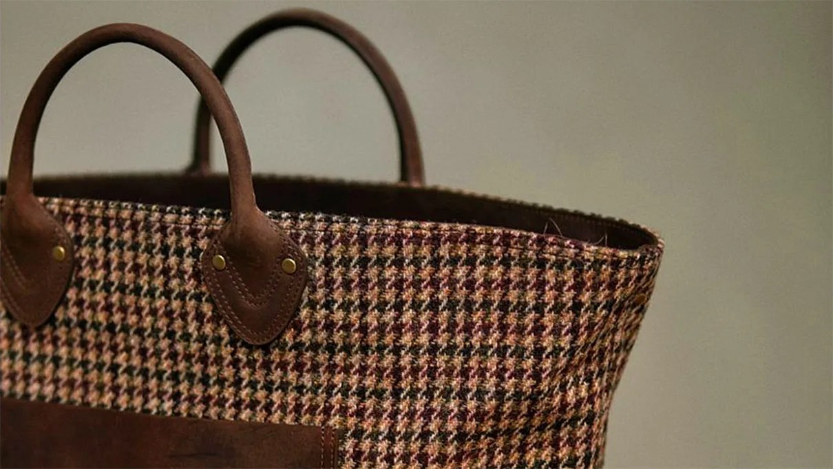 Brown and beige houndstooth fabric tote bag with brown leather handles and trim.