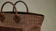 Brown and beige houndstooth fabric tote bag with brown leather handles and trim.