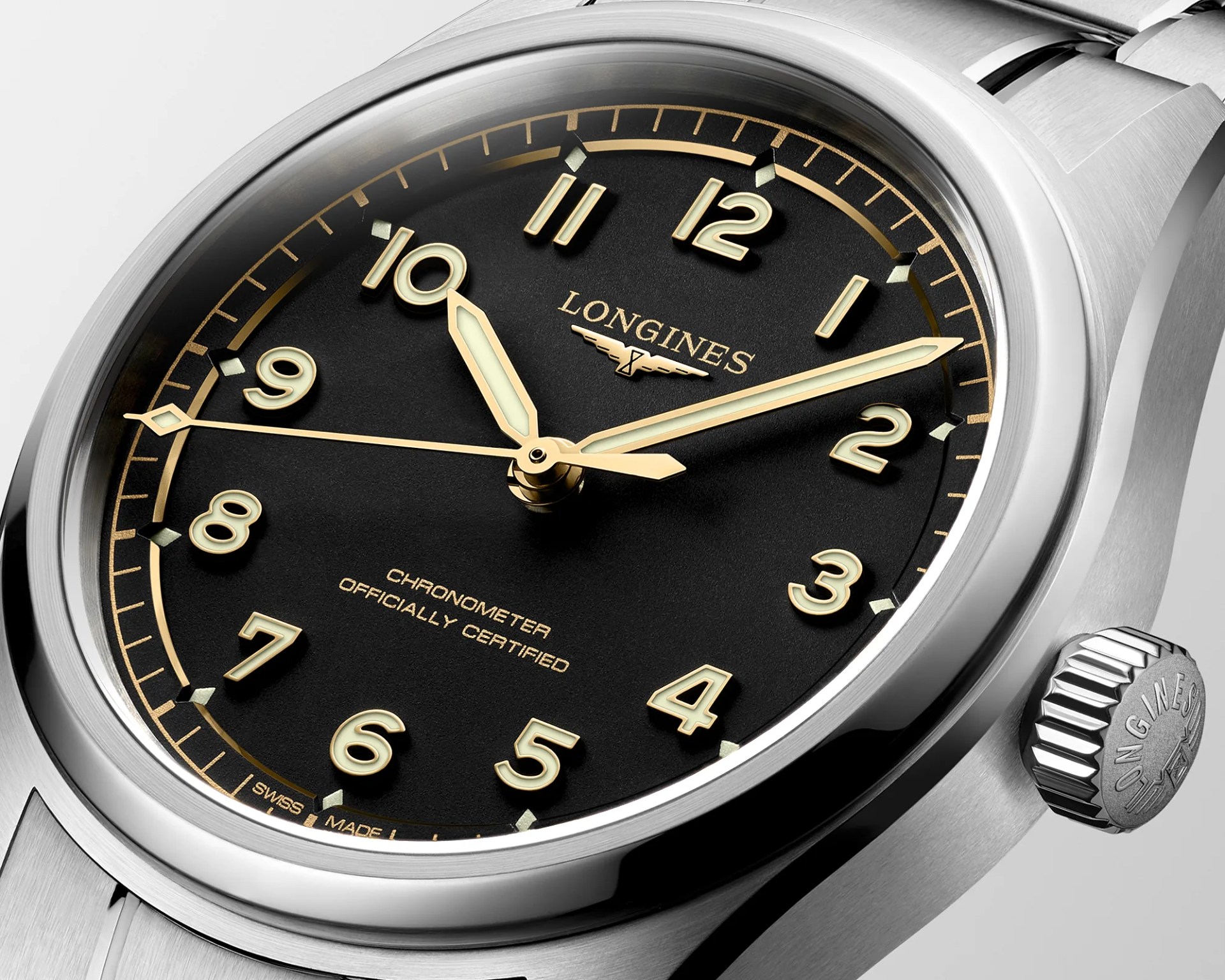 Close-up of a Longines stainless steel wristwatch with a black dial, gold numerals, and luminous hands.