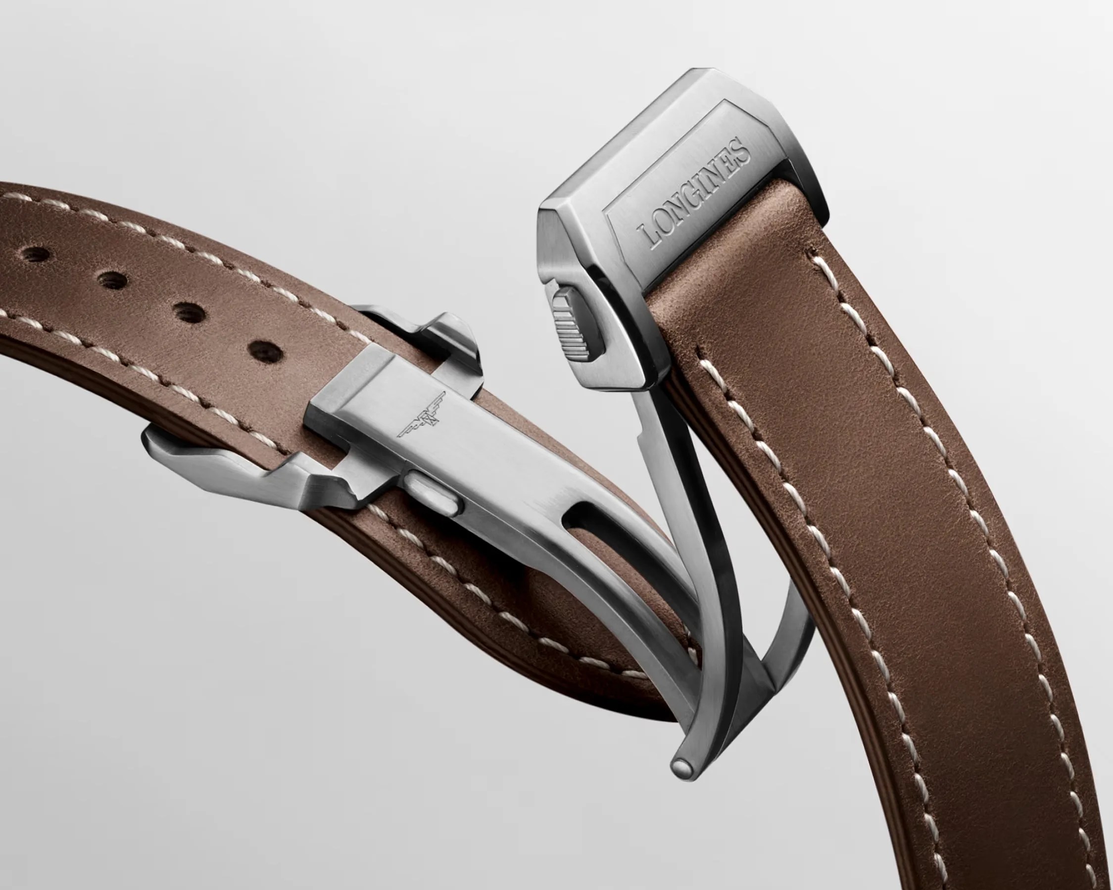 Brown leather watch strap with white stitching and a silver metal clasp engraved with "LONGINES.