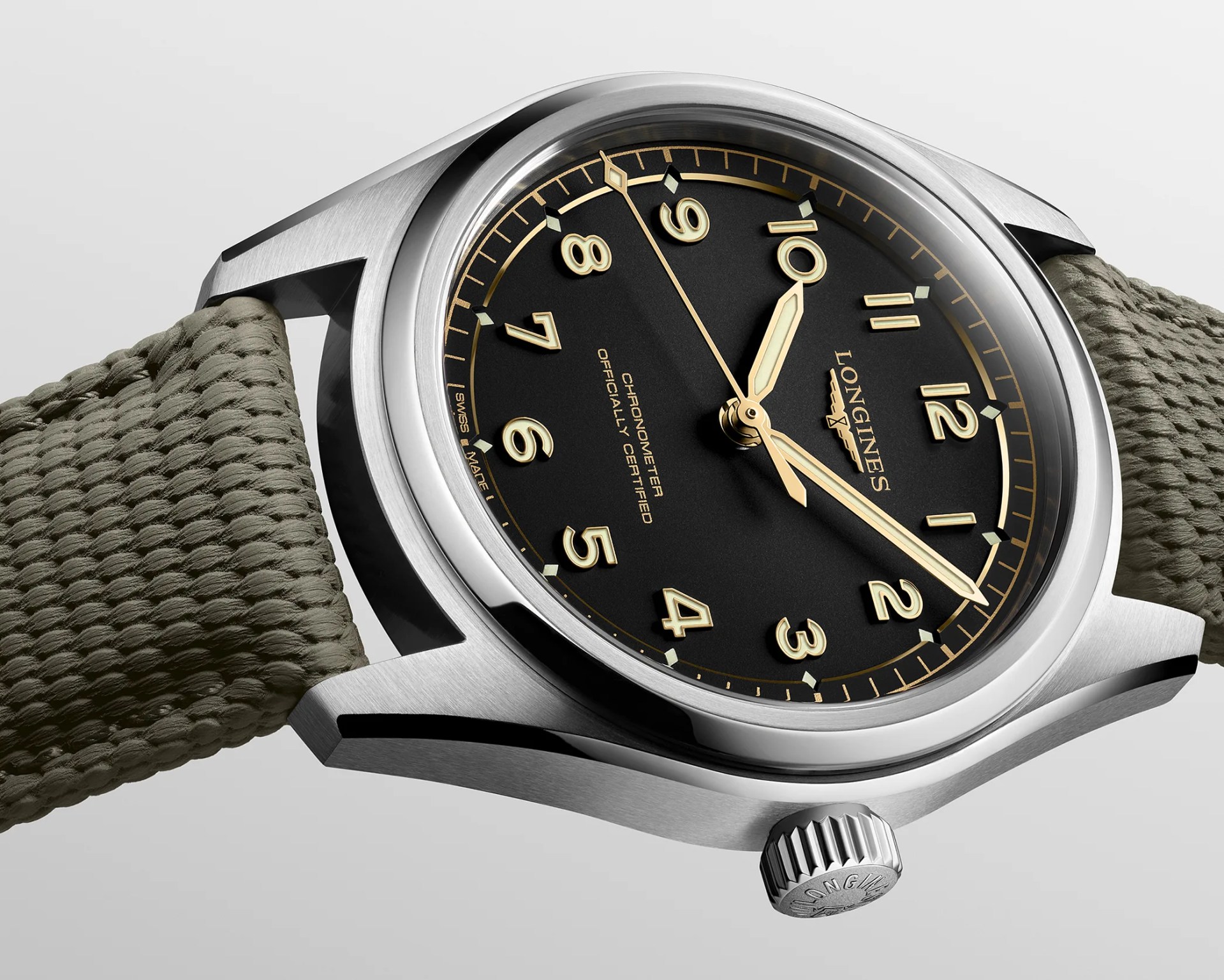 Silver Longines wristwatch with black dial, gold numerals and hands, and olive green woven strap.