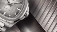 Close-up of a silver wristwatch with a textured gray dial and a ridged crown.