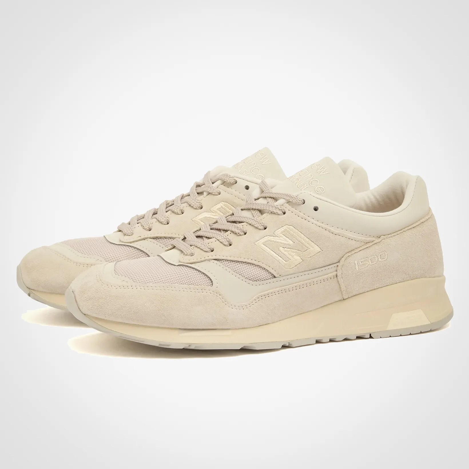 Pair of beige New Balance 1500 sneakers with suede and mesh upper and tonal laces.