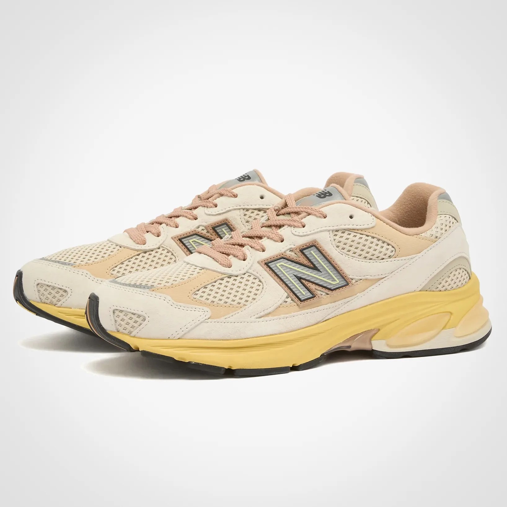 Pair of beige and tan New Balance sneakers with yellow midsoles and black outsoles.