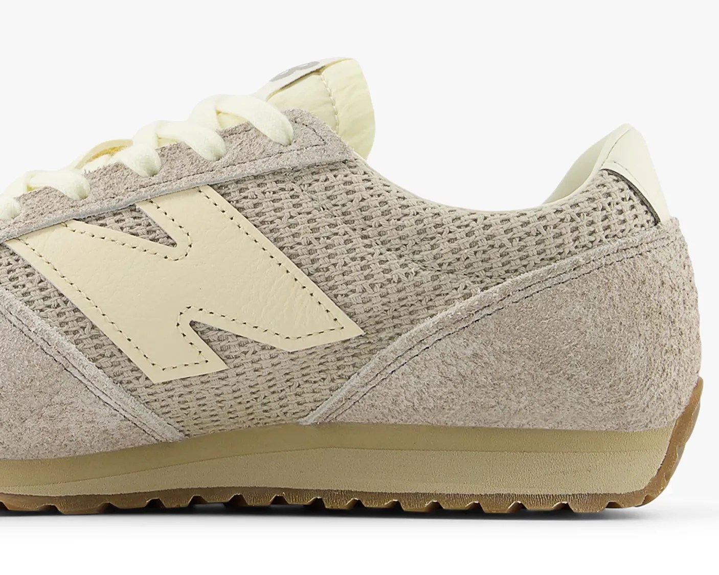 Beige and cream New Balance sneaker with suede and mesh upper and gum sole.