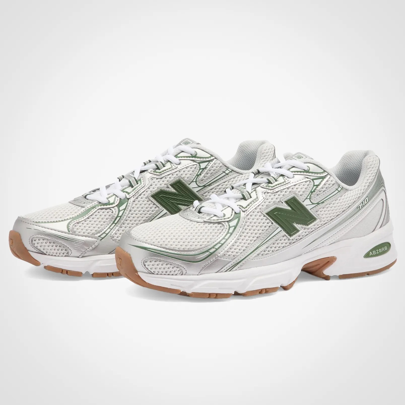 Pair of white and green New Balance 740 sneakers with mesh uppers and gum soles.
