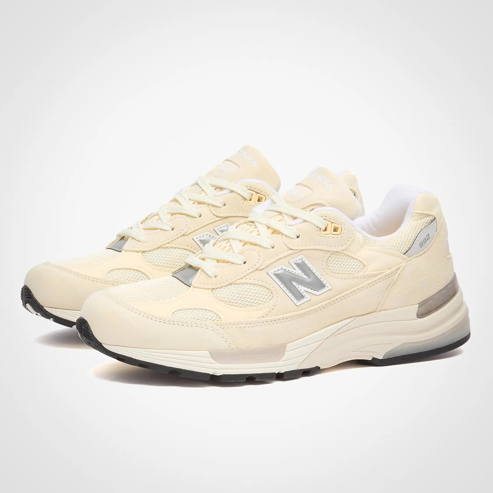 Pair of cream-colored New Balance 992 sneakers with mesh and suede panels and black outsoles.