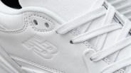 Close-up of white New Balance sneaker with embossed logo and white laces.