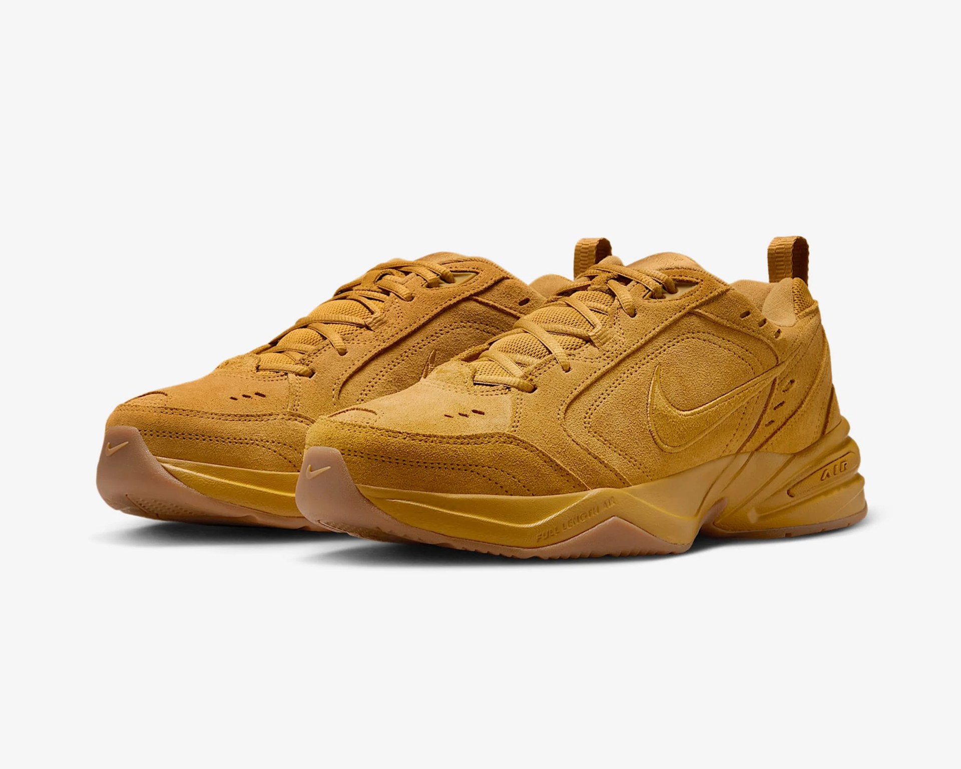 Pair of mustard yellow suede Nike sneakers with lace-up design and rubber soles on a white background.
