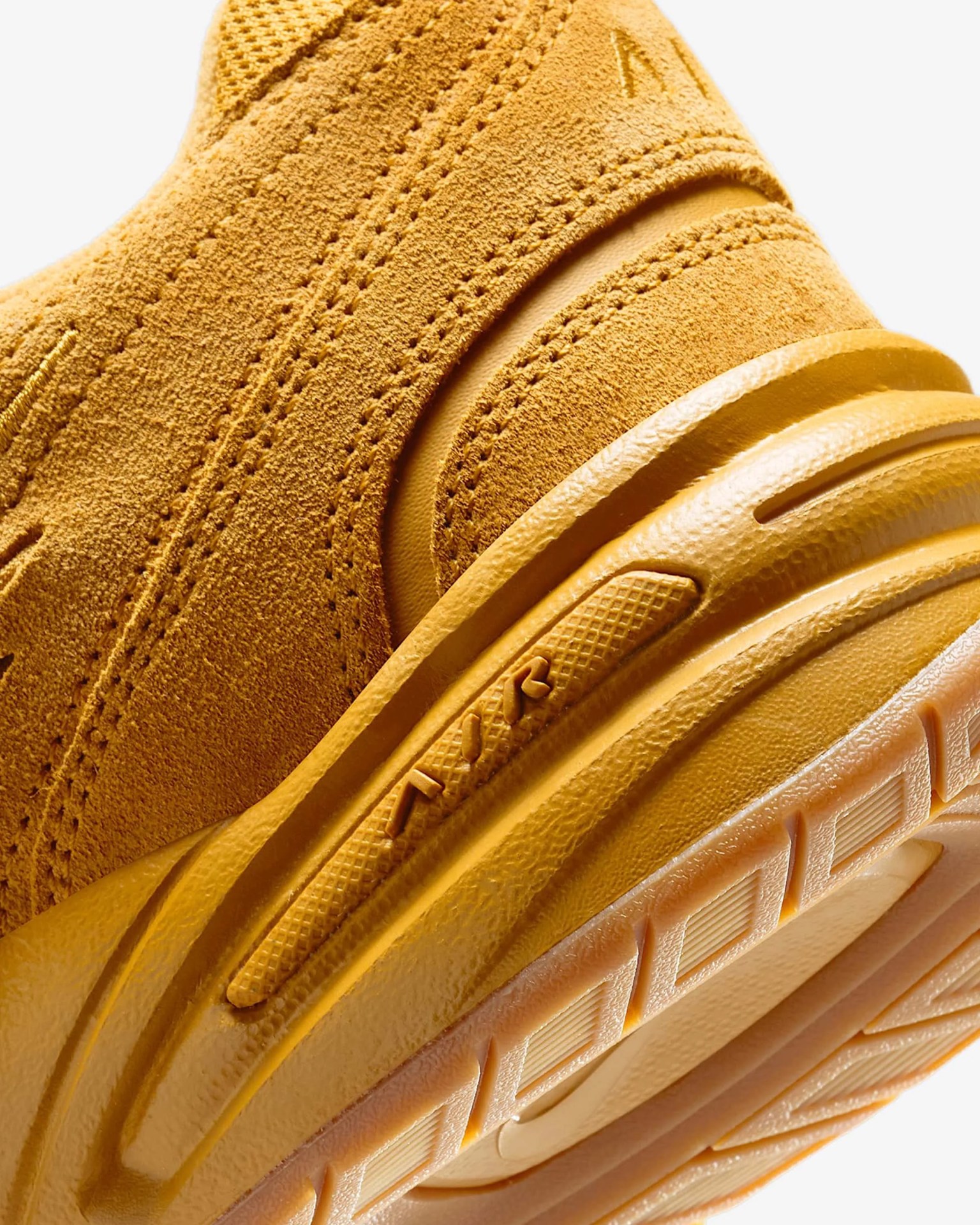Close-up of a mustard yellow suede sneaker heel with detailed stitching and textured rubber sole.