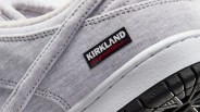 Close-up of a light gray fabric sneaker with a black and white "Kirkland Signature" label and a white midsole with a black textured outsole.