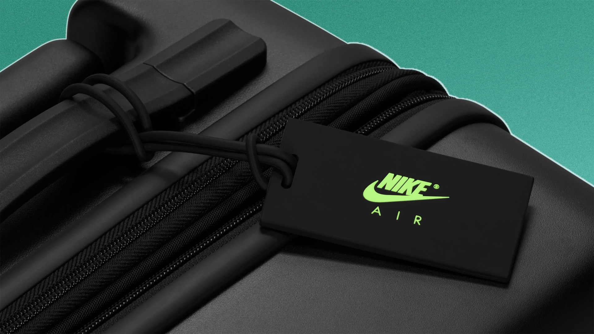 Black luggage tag with neon green Nike Air logo attached to a black suitcase zipper against a teal background.