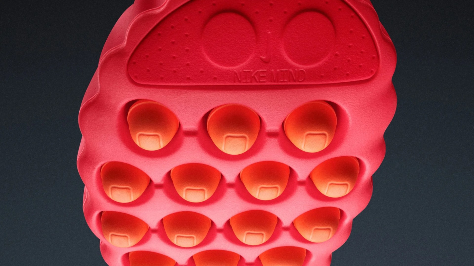 Close-up of a red and orange Nike shoe sole with bubble-like cushioning and "NIKE MIND" embossed on it.