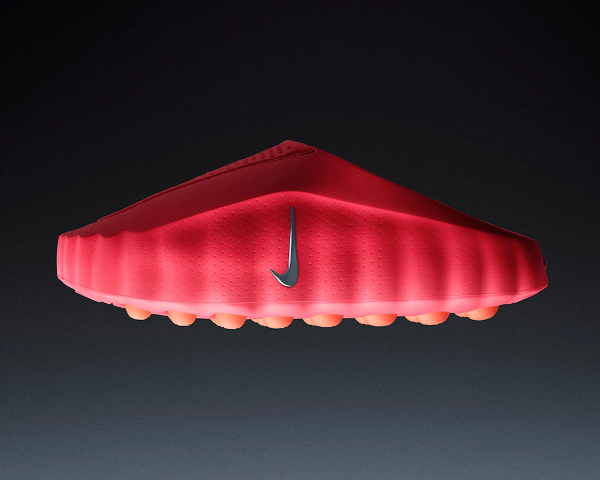 Red Nike slip-on shoe with textured upper and orange rounded sole studs against a dark gradient background.