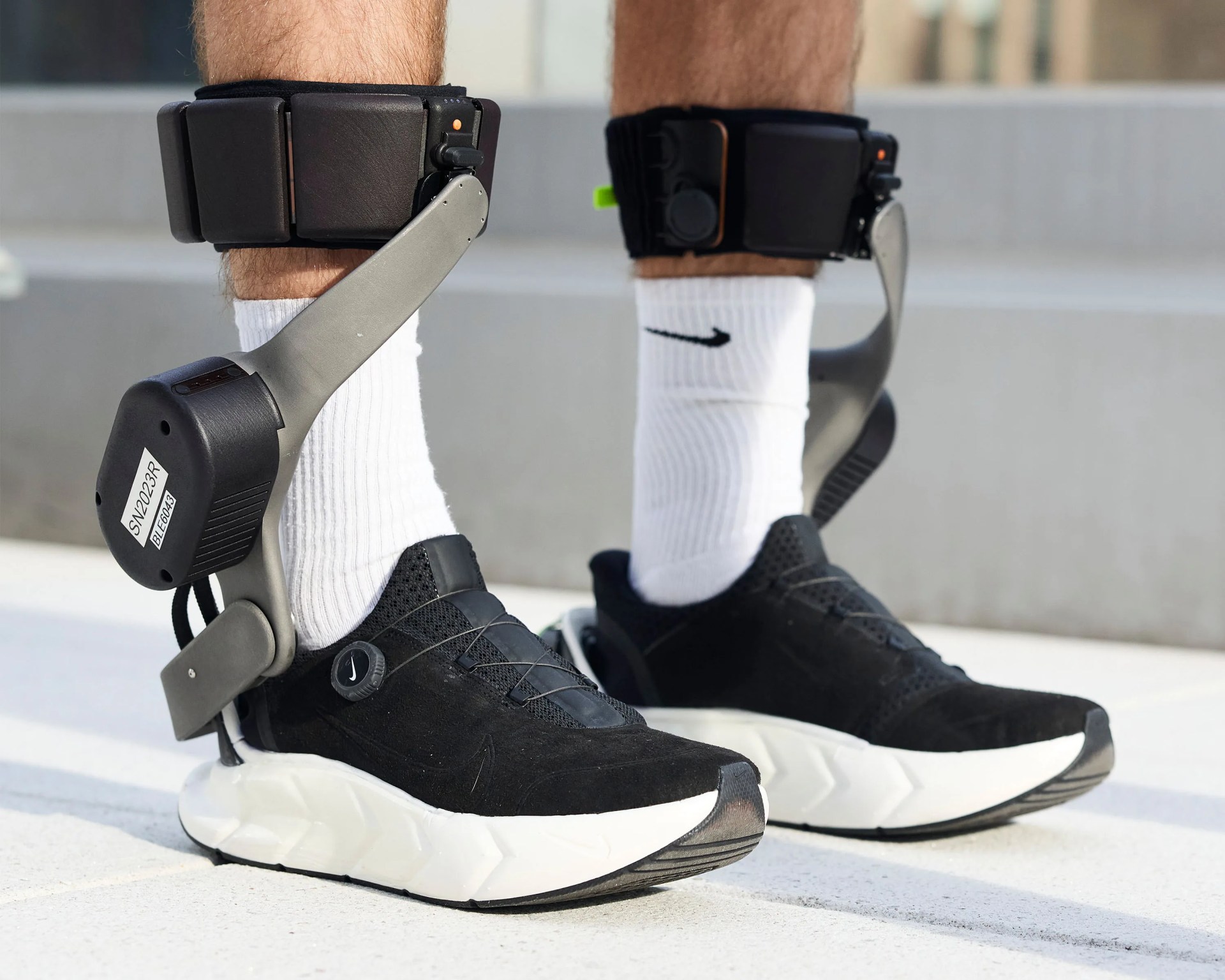 Black and white Nike sneakers with attached gray ankle braces worn with white Nike socks.