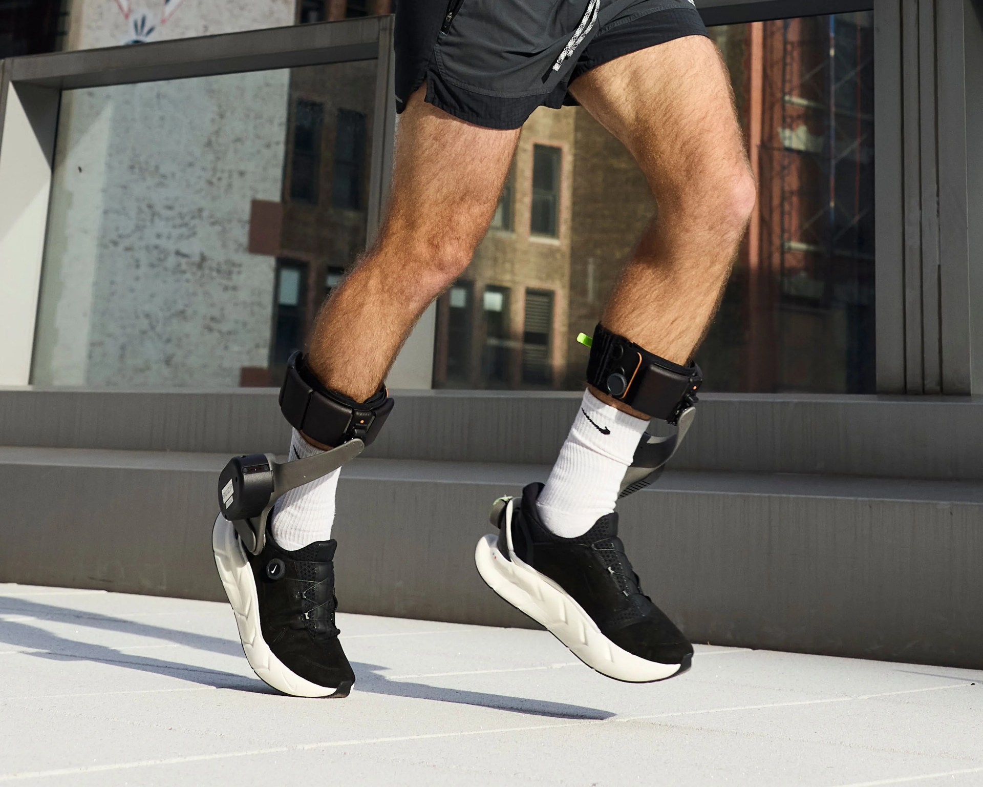 Legs wearing black and white Nike sneakers with attached ankle devices and white Nike socks.