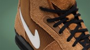 Close-up of a brown suede and mesh sneaker with black laces and a white Nike swoosh logo.
