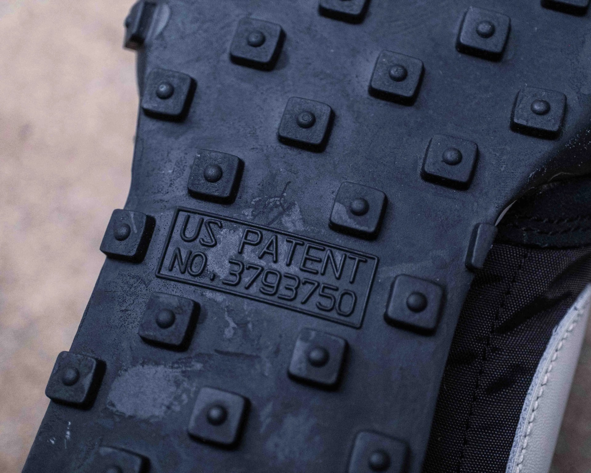 Close-up of a black rubber shoe sole with square studs and the text "US PATENT NO. 3793750" embossed.