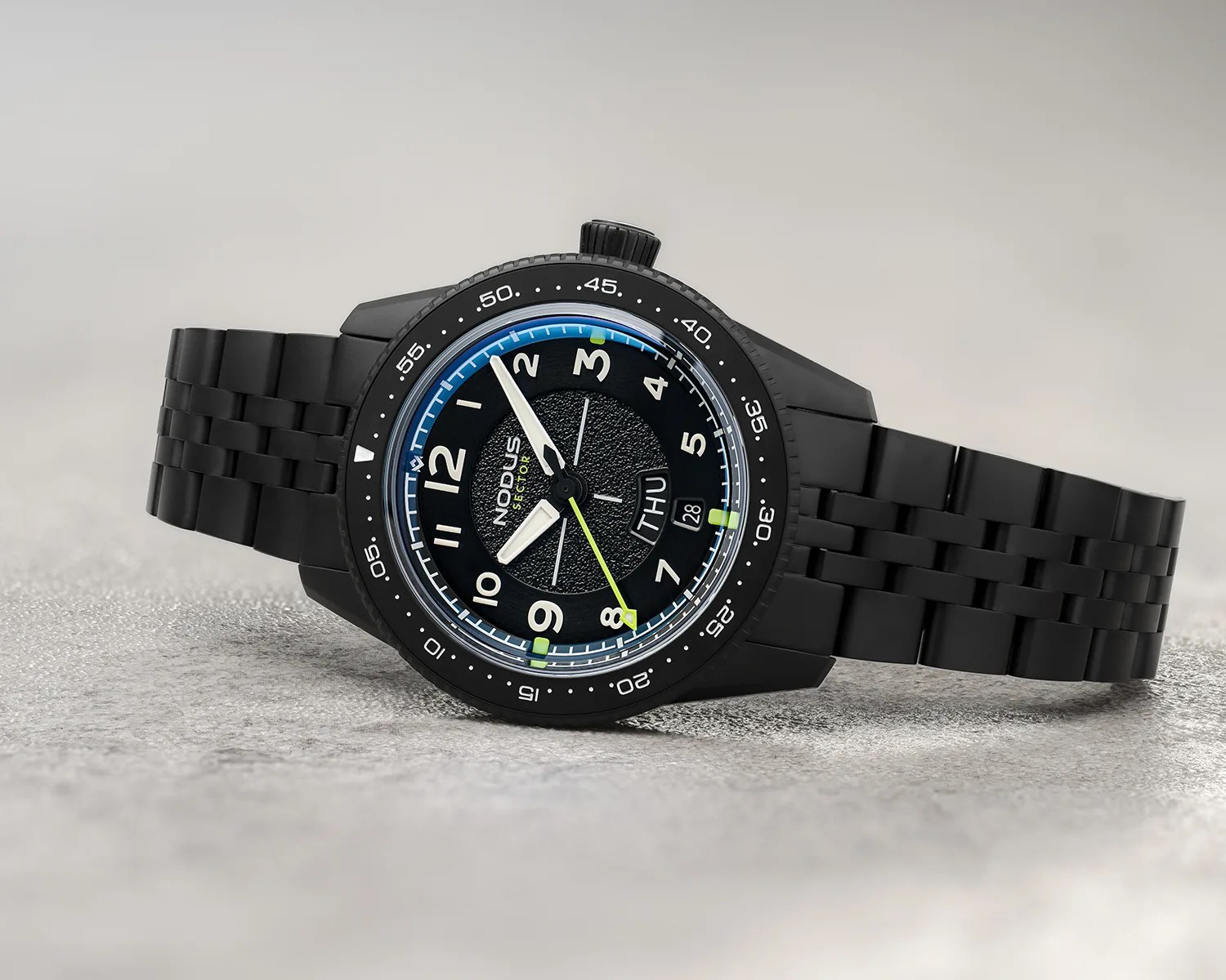 Black metal wristwatch with luminous white hands, green second hand, and day-date display on textured black dial.