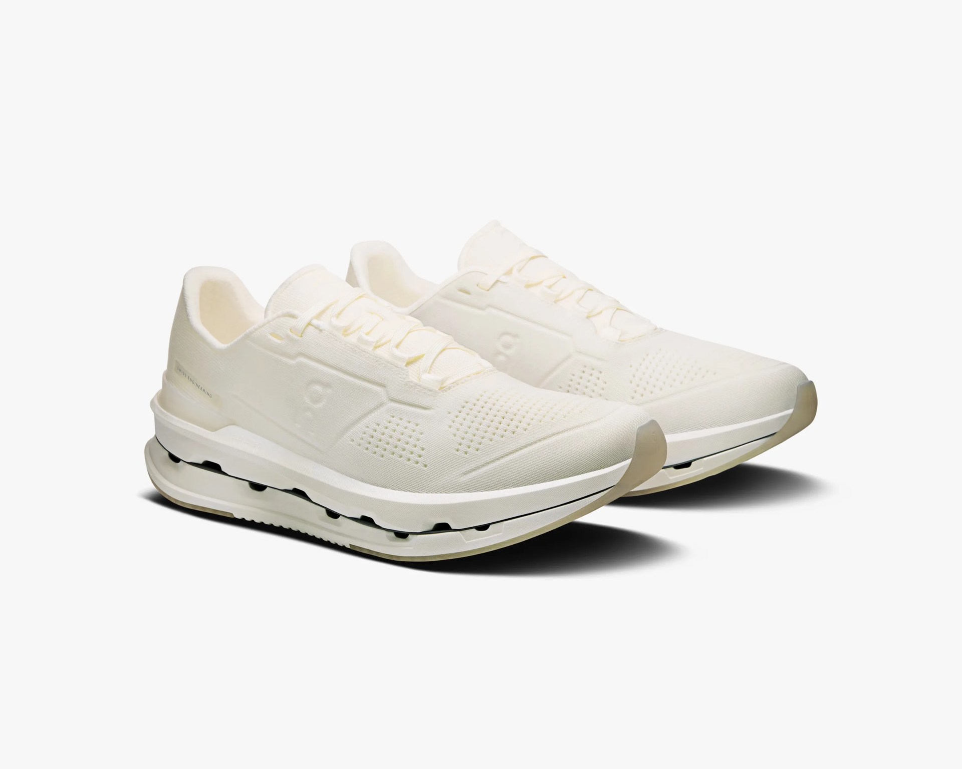 Pair of off-white athletic running shoes with cushioned soles and subtle perforated design.