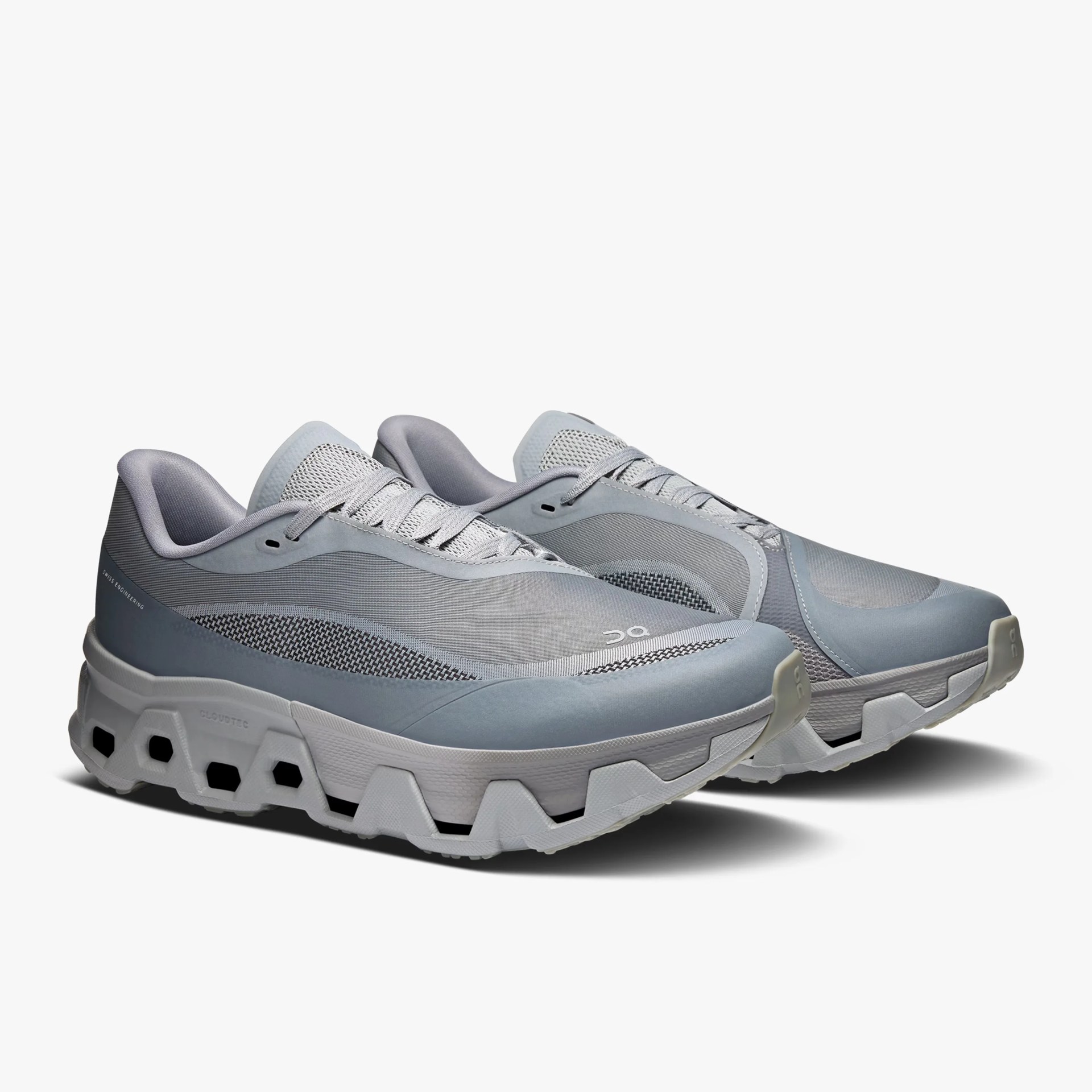 Pair of light gray athletic shoes with mesh uppers and thick white soles featuring hexagonal cutouts.
