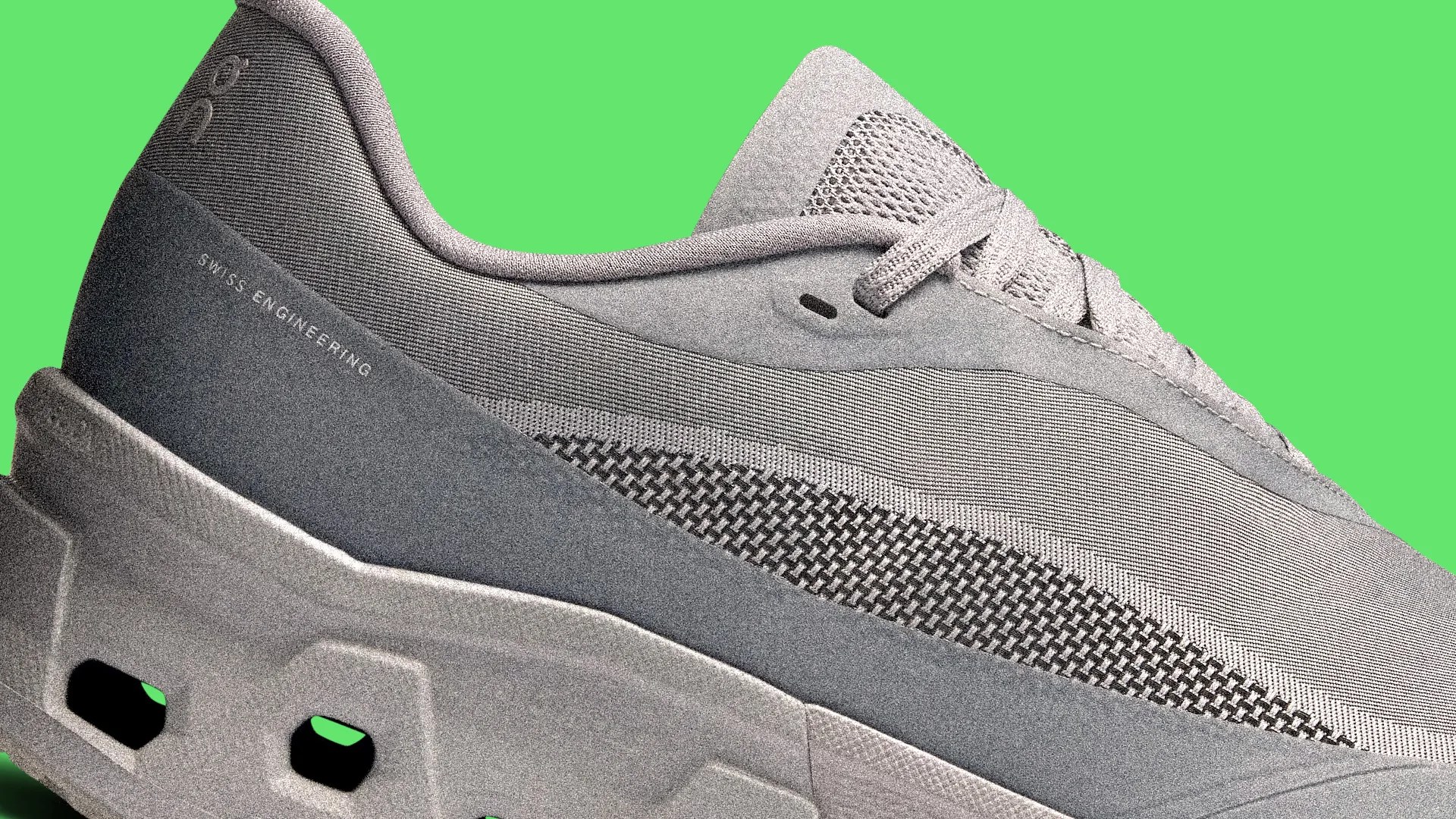 Close-up of a gray sneaker with textured fabric and "Swiss Engineering" text on the heel against a green background.