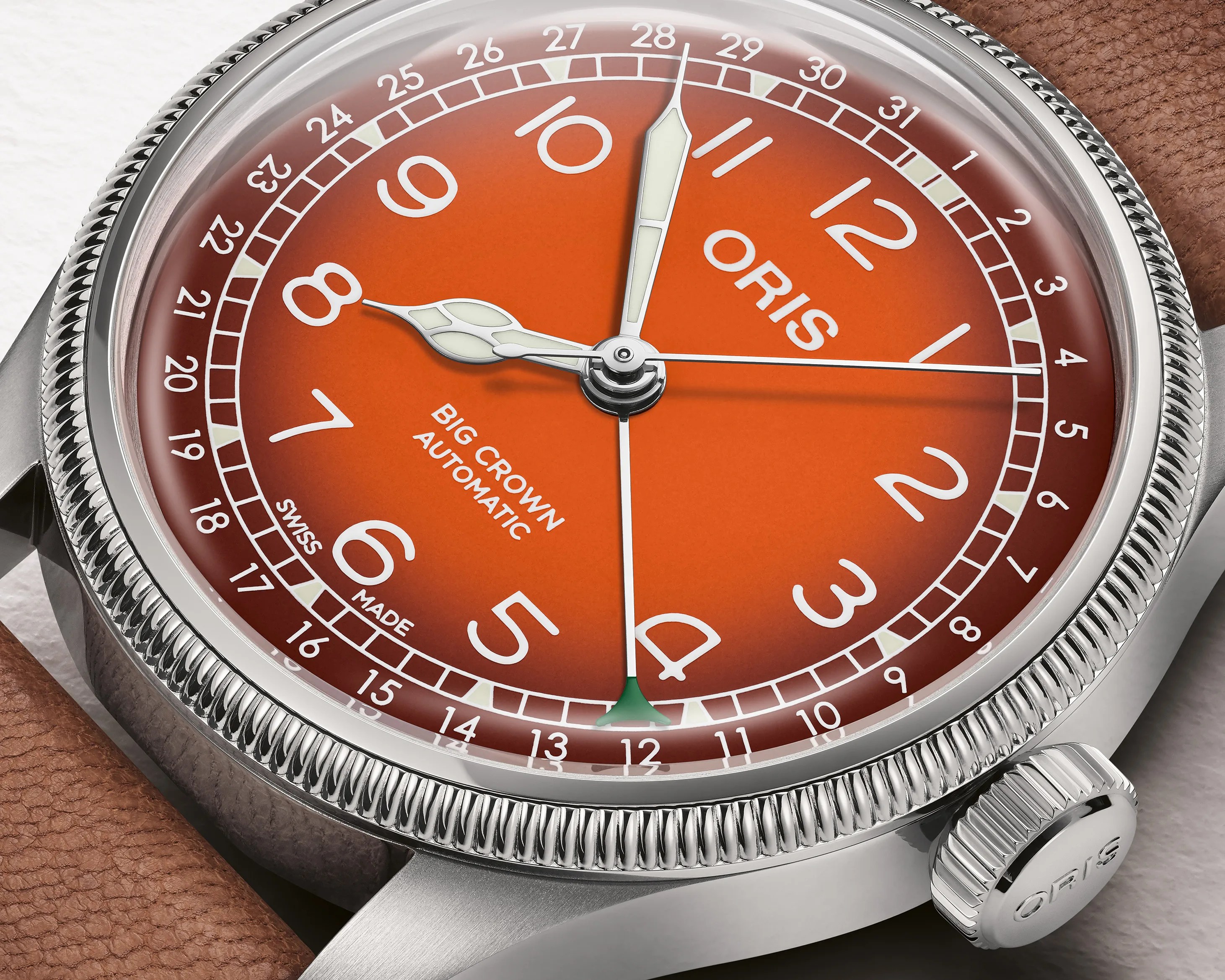 Close-up of an Oris Big Crown Automatic watch with an orange dial, white numerals, and a brown leather strap.
