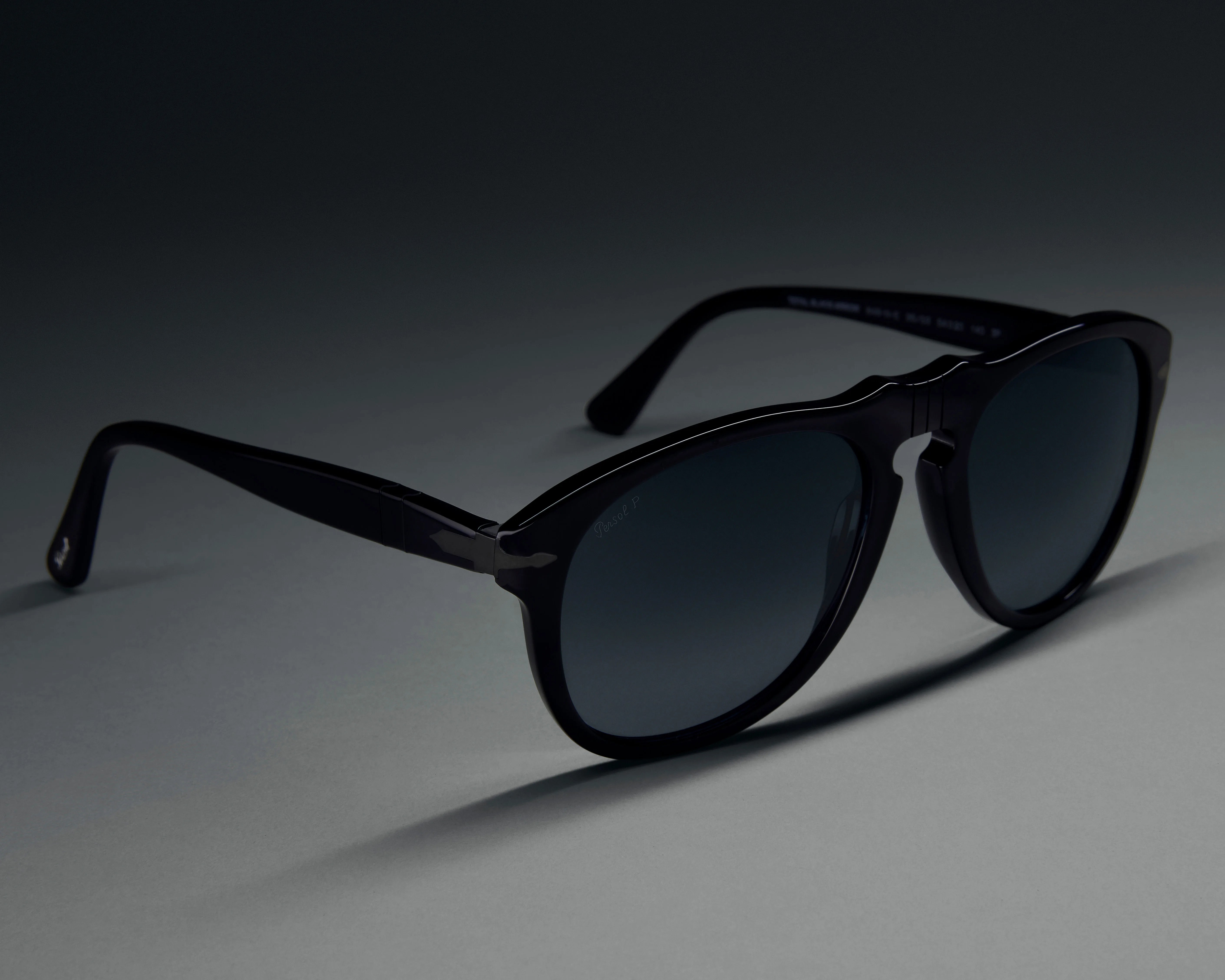 Black plastic frame sunglasses with dark tinted lenses on a gray surface.