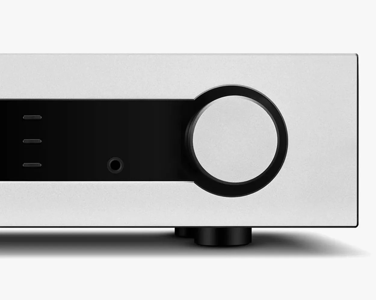 Close-up of a silver and black audio amplifier front panel with a large round knob and three small indicator lights.
