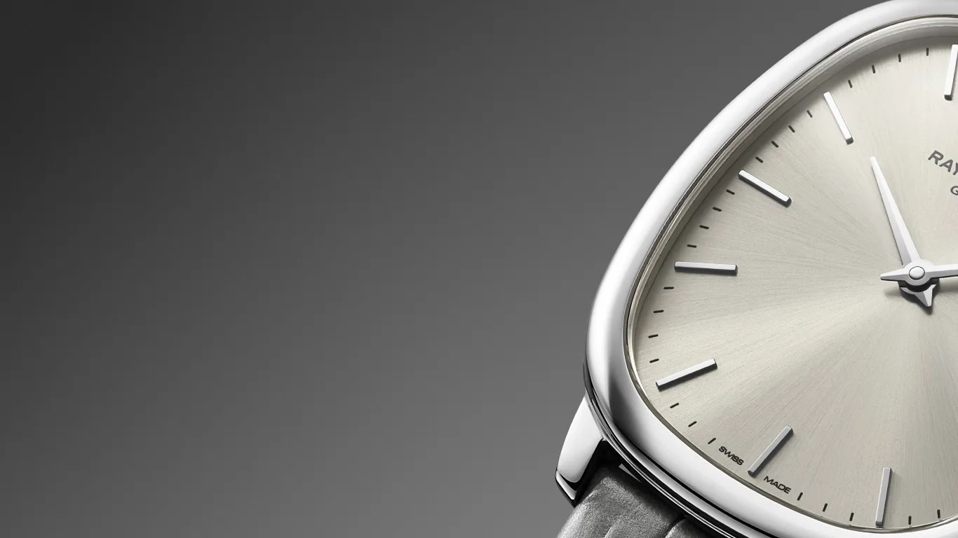 Close-up of a silver-toned watch face with minimalist hour markers and a black leather strap.