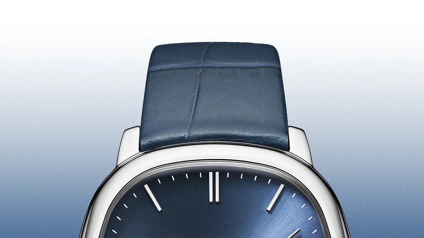 Silver watch with a rounded square case, blue sunburst dial, and blue leather strap.